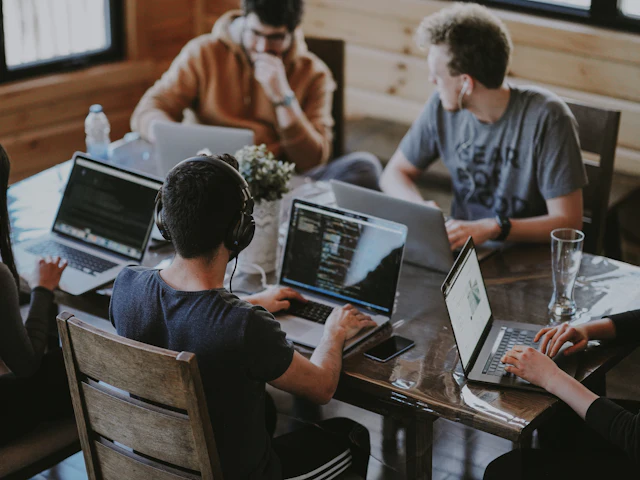 A small team working together around laptops at a shared table