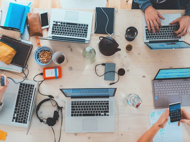 Team members working on several laptops around one table