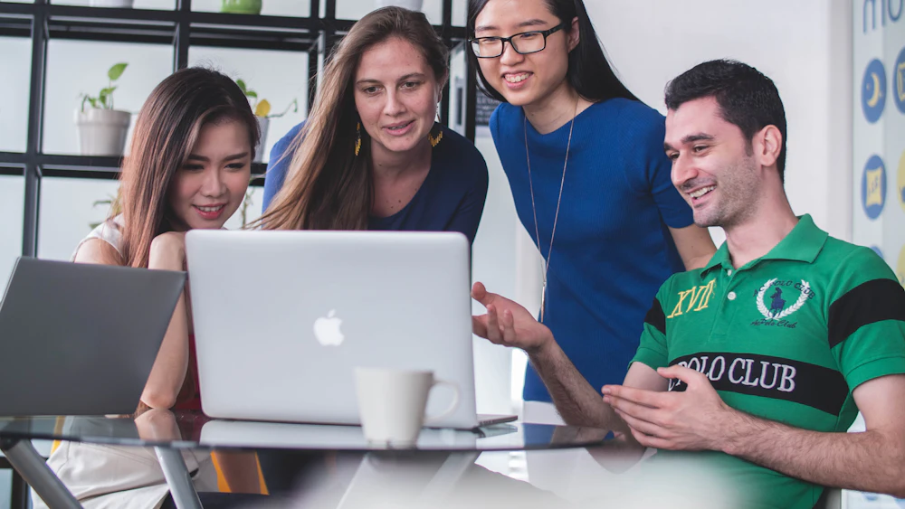 Four people reviewing work together on a laptop